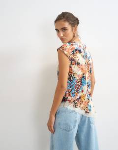 Model wearing Floral cap sleeve asymmetric tie front lace detail top in ecru