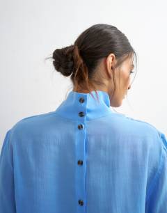 Model wearing Funnel neck backwards long sleeve shirt in cornflour blue