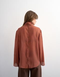 Model wearing Funnel neck backwards long sleeve shirt in rust