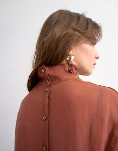 Model wearing Funnel neck backwards long sleeve shirt in rust