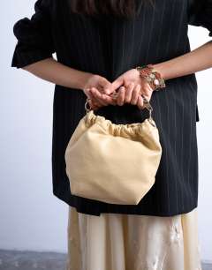 Model wearing Gabriette metal trim handle grab bag in buttermilk