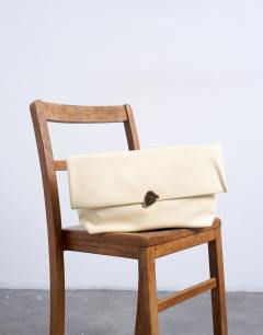 Model wearing Gaia folded clutch with hardware in buttermilk yellow