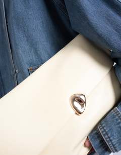 Model wearing Gaia folded clutch with hardware in buttermilk yellow