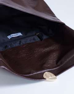 Model wearing Gaia large clutch bag with gold hardware in chocolate