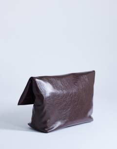 Model wearing Gaia large clutch bag with gold hardware in chocolate