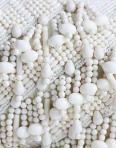 Model wearing Garison bead and embellished clutch in white