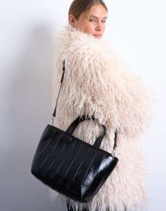 Model wearing Gemma medium stripe faux leather grab bag in black