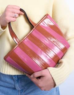 Model wearing Gemma medium stripe faux leather grab bag in pink and brown