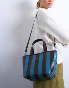 Model wearing Gemma stripe faux leather grab bag in blue and brown