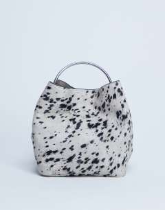 Model wearing Gene real leather grab bag with metal handle in cow dalmatian