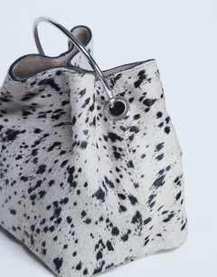 Model wearing Gene real leather grab bag with metal handle in cow dalmatian