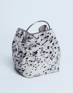 Model wearing Gene real leather grab bag with metal handle in cow dalmatian