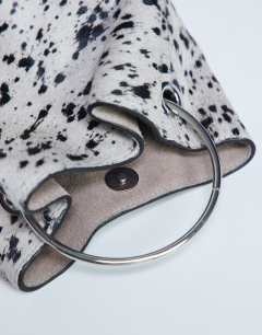 Model wearing Gene real leather grab bag with metal handle in cow dalmatian