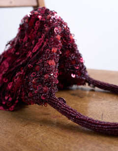 Model wearing Giana sequin tassel grab bag in burgundy
