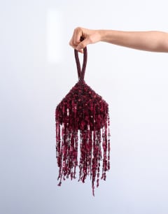 Model wearing Giana sequin tassel grab bag in burgundy