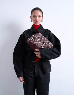 Model wearing Gideon large studded clutch bag in burgundy