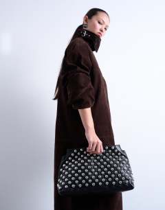 Model wearing Gideon studded clutch bag in black