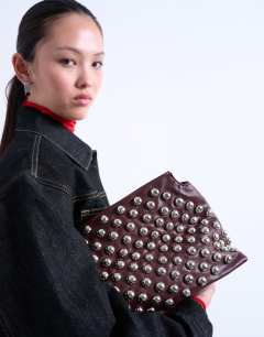 Model wearing Gideon studded clutch bag in burgundy