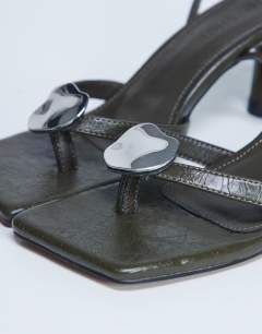 Model wearing Gilly heeled toe thong with metal detail in khaki