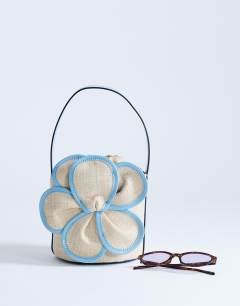 Model wearing Gino straw flower grab bag in light blue