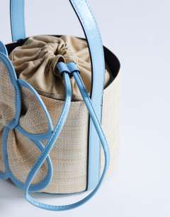 Model wearing Gino straw flower grab bag in light blue