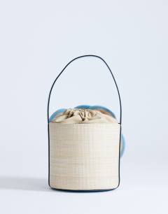 Model wearing Gino straw flower grab bag in light blue