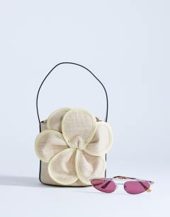 Model wearing Gino straw flower grab bag in yellow