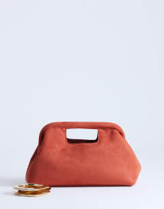Model wearing Gordan clutch with handle in burnt orange