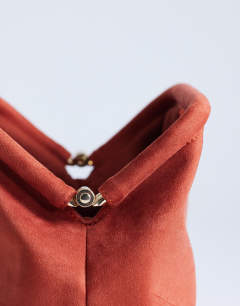 Model wearing Gordan clutch with handle in burnt orange