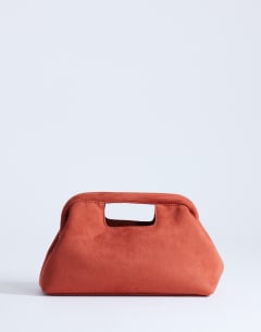 Model wearing Gordan clutch with handle in burnt orange