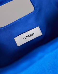 Model wearing Gordan medium suedette clutch with handle in cobalt