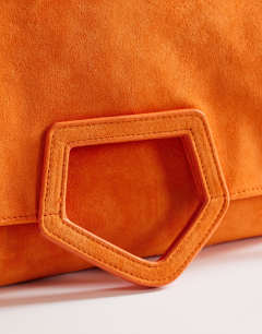 Model wearing Gregry oversized folded clutch bag in orange suedette