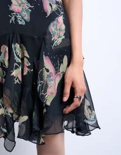 Model wearing Hanky hem mini dress with pinched straps in black based floral