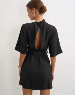 Model wearing Heavy crepe asymmetric neck structured shoulder pad mini dress with belt in black