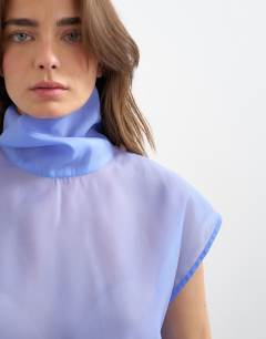 Model wearing High neck grown on shoulder sheer organza top in cornflour blue