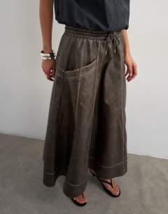 Model wearing High shine leather look maxii skirt with side pockets in washed brown