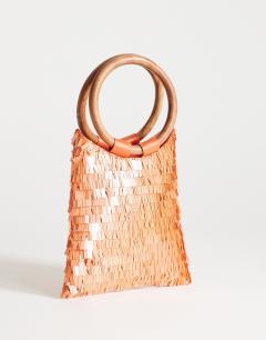 Model wearing Holly sequin grab bag with wooden handle in coral