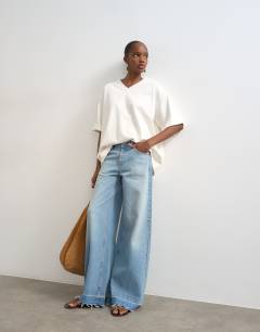 Model wearing Horizon mid rise wide leg jean with let down hem detail in vintage blue