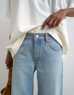 Model wearing Horizon mid rise wide leg jean with let down hem detail in vintage blue