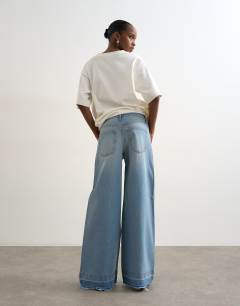 Model wearing Horizon mid rise wide leg jean with let down hem detail in vintage blue