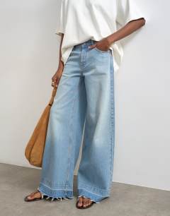 Model wearing Horizon mid rise wide leg jean with let down hem detail in vintage blue