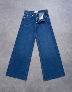 Model wearing Horizon mid rise wide leg jean with raw hem in rich blue