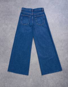 Model wearing Horizon mid rise wide leg jean with raw hem in rich blue