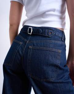 Model wearing Hourglass Cinch low rise relaxed jean in raw look indigo 