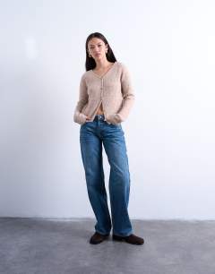 Model wearing Hourglass Ember low rise straight leg jean in mid blue