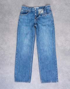 Model wearing Hourglass Ember low rise straight leg jean in mid blue