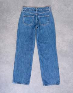 Model wearing Hourglass Ember low rise straight leg jean in mid blue