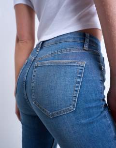 Model wearing Hourglass Jamie Flare high rise jeans in vintage blue