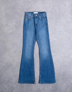 Model wearing Hourglass Jamie Flare high rise jeans in vintage blue