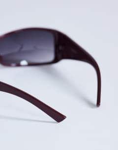 Model wearing Ibiza wrapround rectangle sunglasses in burgundy